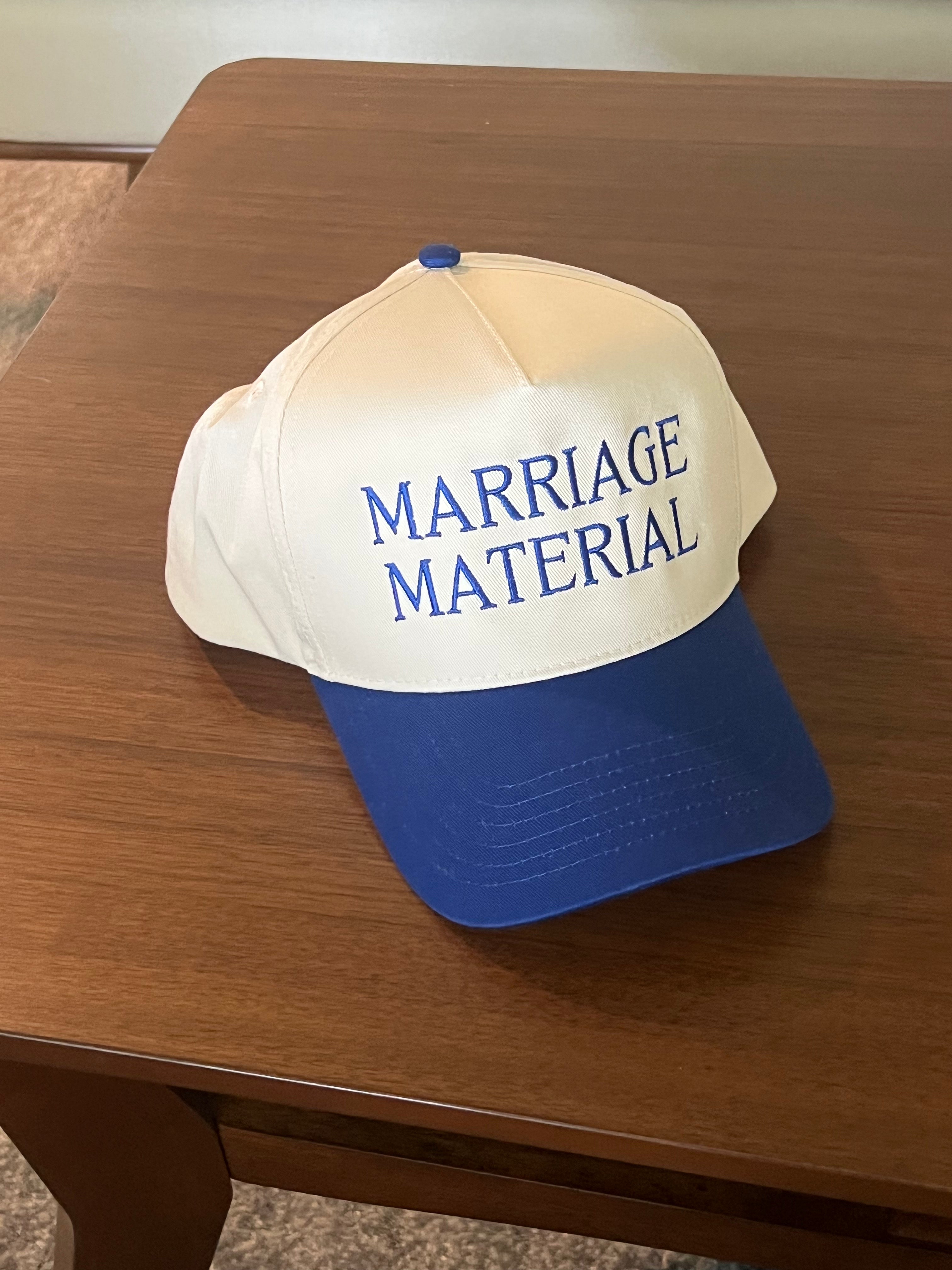 Cap with 'MARRIAGE MATERIAL' text on a wooden surface