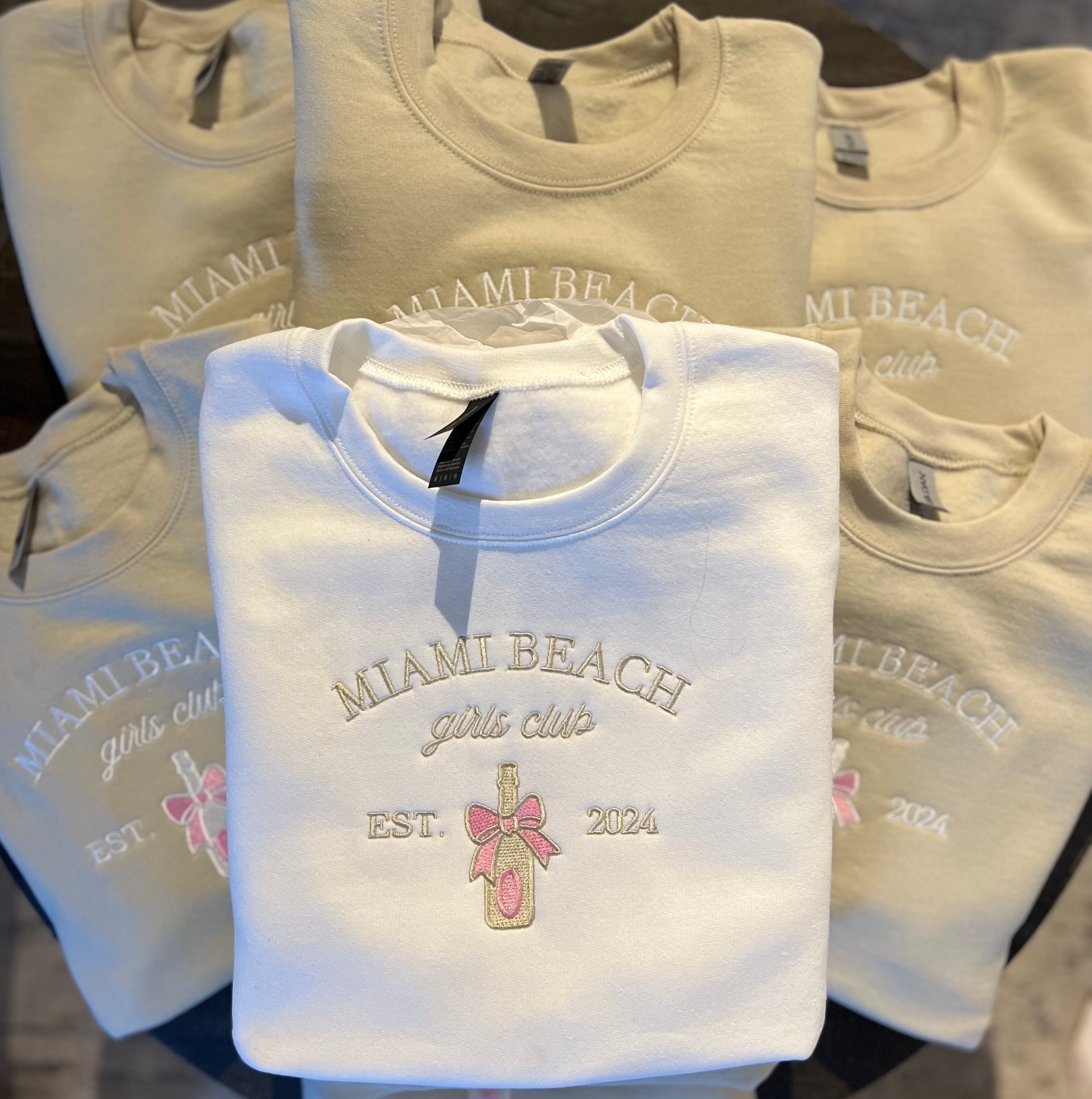 A collection of custom embroidered sweatshirts with various texts and designs in neutral colors