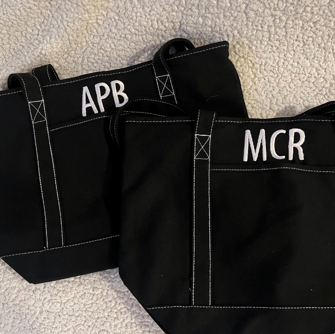 Two black bags with 'APB' and 'MCR' labels on a textured surface.