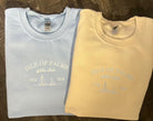 Two crewneck sweatshirts, one in blue and one in a beige color, each with a embroidered sailboat design and the text 'ISLE OF PALMS YACHT CLUB'.
