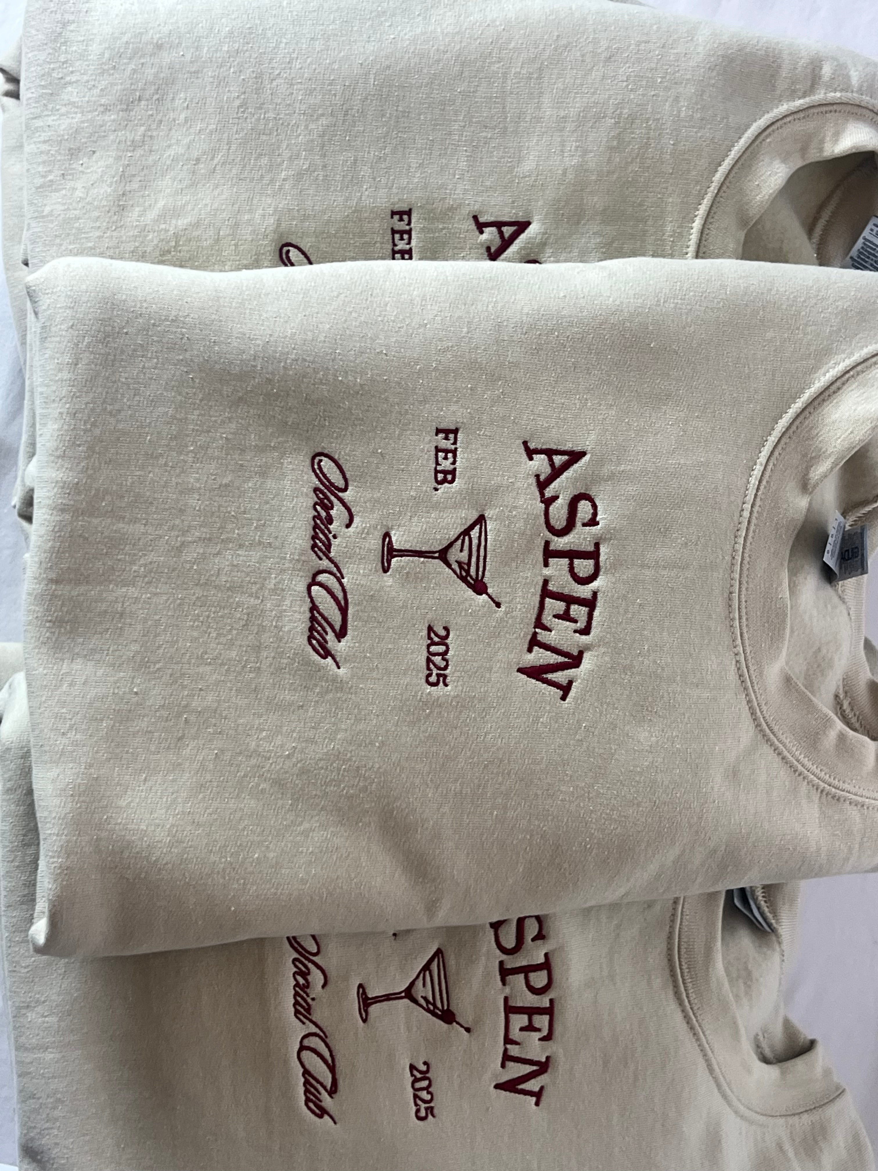 A collection of embroidered sweatshirts with 'ASPEN' text embroidered on them, displayed in a stacked arrangement.